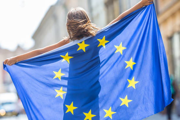 eu の旗。欧州連合の旗とかわいい幸せな女の子。市では、欧州連合の旗を振って若い 10 代の少女 - european community european union flag europe flag ストックフォトと画像