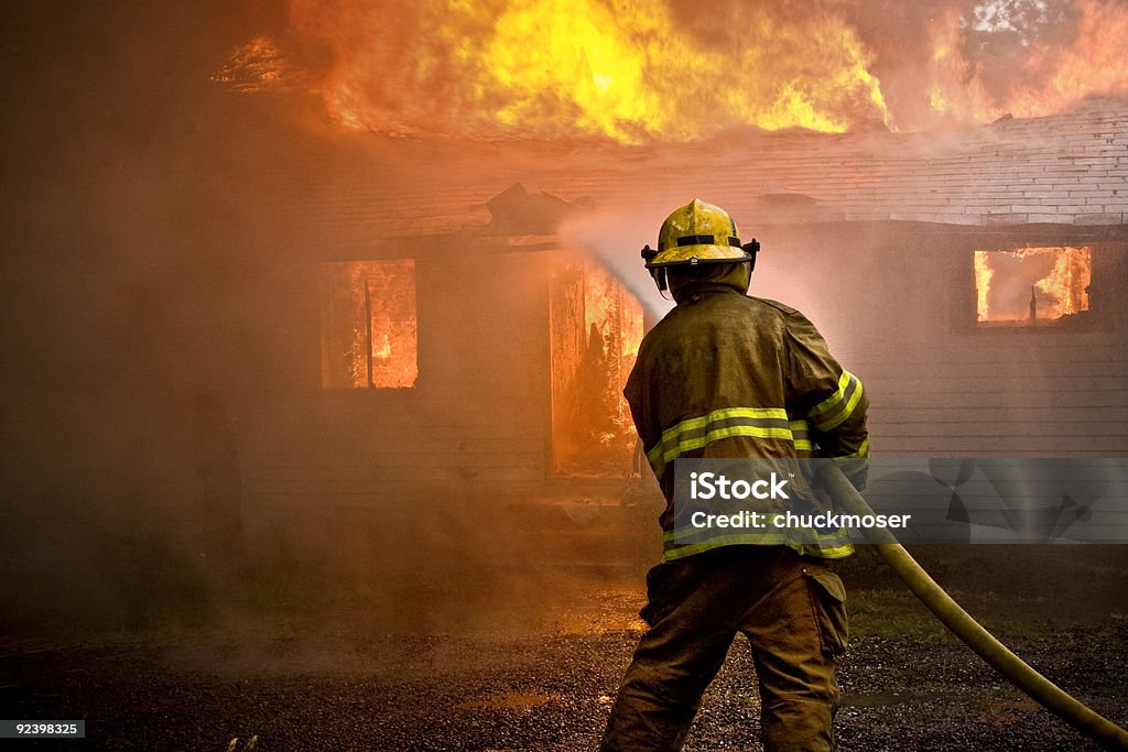 Bombeiro jogando água em uma casa de incêndio - Foto de stock de Fogo royalty-free