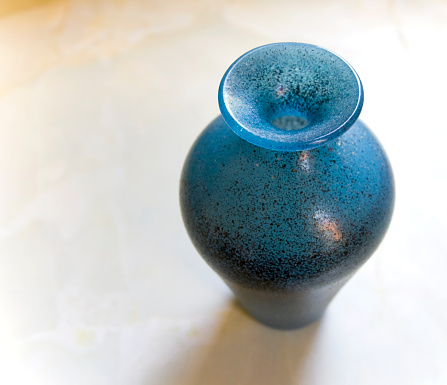 Roman-style blue glass vase standing on a pale marble surface.