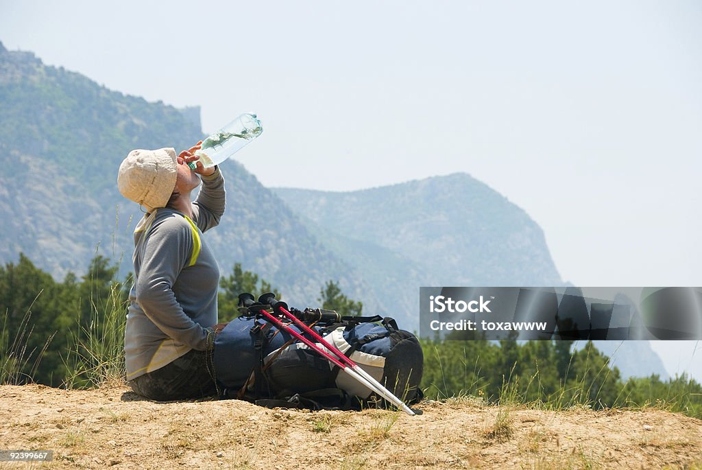 Cansado alpinista bebidas água de uma garrafa na montanhas - Foto de stock de Adulto royalty-free