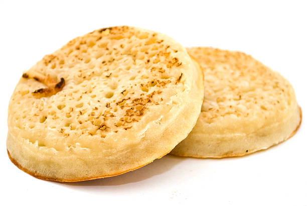 Two hot crumpets with melting butter - studio shot with a shallow depth of field and a white background