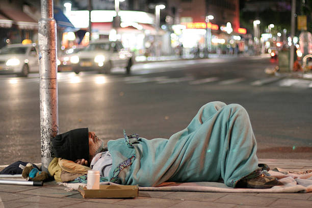 male homeless sleeping in a street stock photo