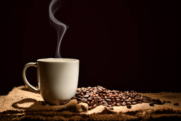 tazza di caffè con fumo e chicchi di caffè su sfondo nero - fresh coffee foto e immagini stock