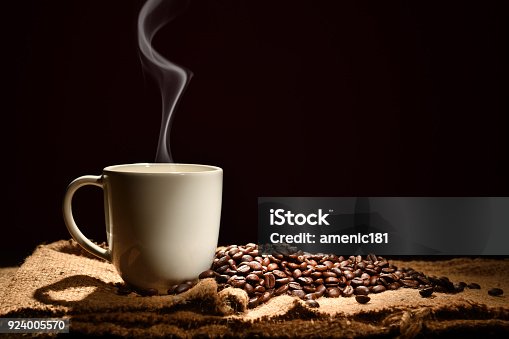 istock Cup of coffee with smoke and coffee beans on black background 924005570
