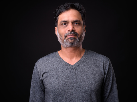 Studio Portrait Of Indian Man Against Black Background