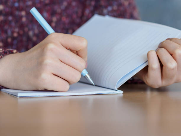 istock Close up of woman's hands writing in notepad placed on wooden desktop. 924015696
