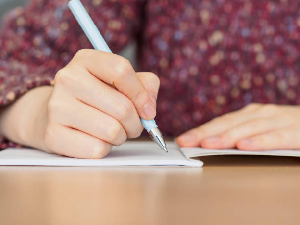 istock Close up of woman's hands writing in notepad placed on wooden desktop. 924015808