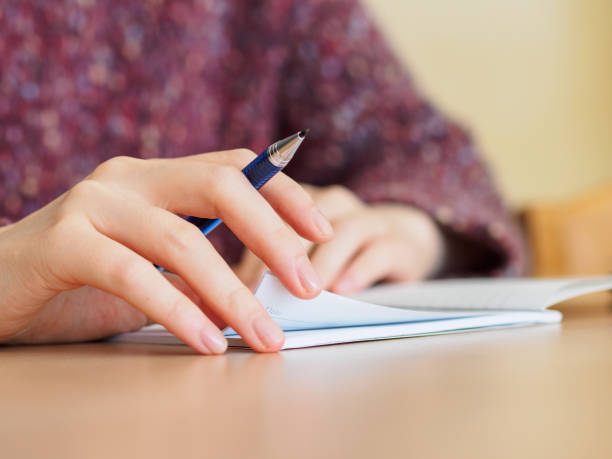 istock Close up of woman's hands hold a Mechanical pencil put on notepad placed on wooden table. 924016432