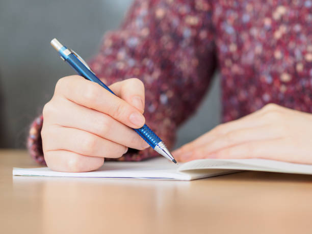 istock Close up of woman's hands writing in notepad placed on wooden desktop. 924016974