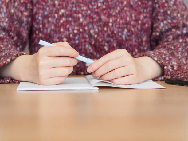 istock Close up of woman's hands hold a pen with notepad placed on wooden table. 924019688