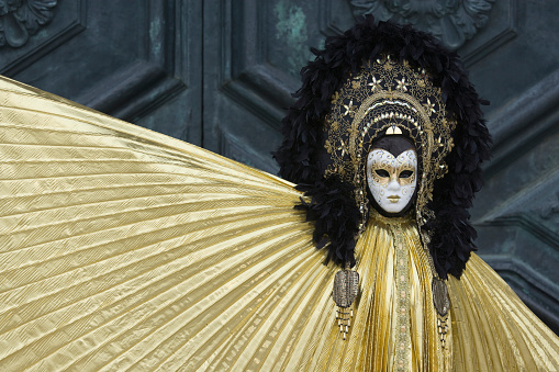 Close up of black and white carnival mask with golden bells at City of Venice on a cloudy summer day. Photo taken August 6th, 2023, Venice, Italy.