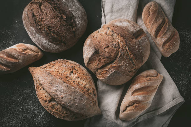 istock Flat-lay of various bread selection. Multigrain rustic bread on kitchen towels over grey background, top view, copy space 924023302