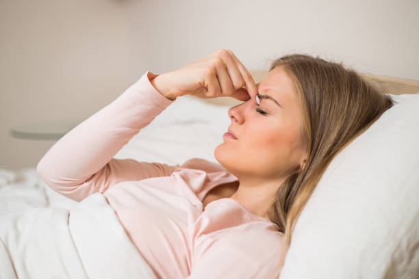 Woman having headache Woman having strong headache while lying in bedroom. sinusitis photos stock pictures, royalty-free photos & images