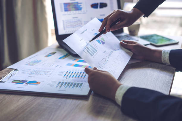 istock financial Image of two  business people pointing at business document presentation summary report , during discussion at meeting , Notebook on wood table 924052032