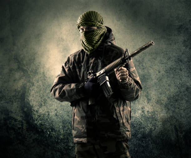 portrait of a heavily armed masked soldier with grungy background - terrorism imagens e fotografias de stock