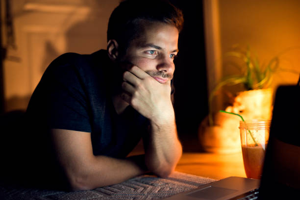 istock Young man lying on floor with laptop, reading interesting articles 924069418