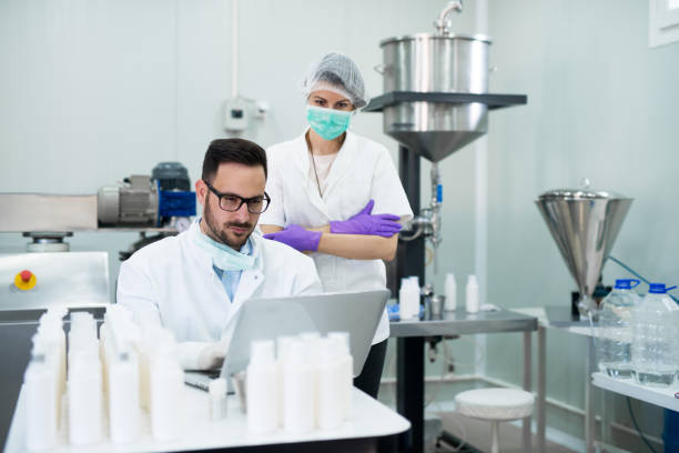 istock Young successful technologist making face care creams with his assistant. Working with high tech equipment. 924072692