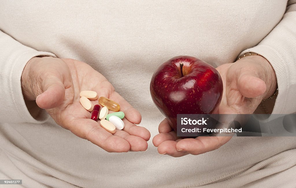 Пожилая женщина, держа таблетки и Apple - Стоковые фото 60-64 года роялти-фри