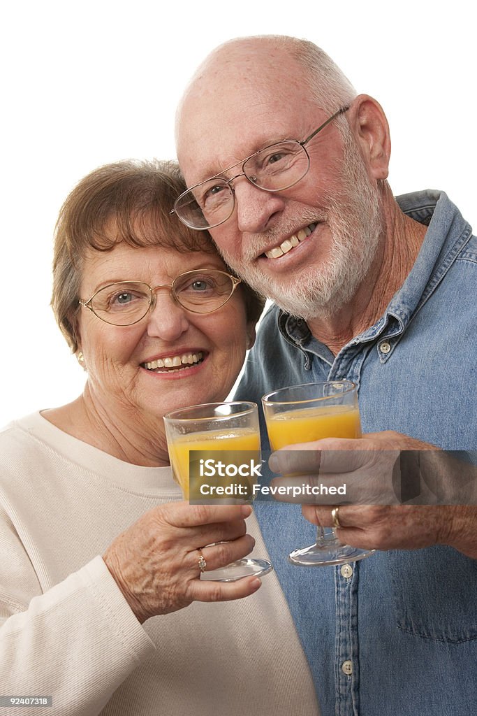 Felice coppia Senior con bicchieri di succo d'arancia - Foto stock royalty-free di 60-64 anni