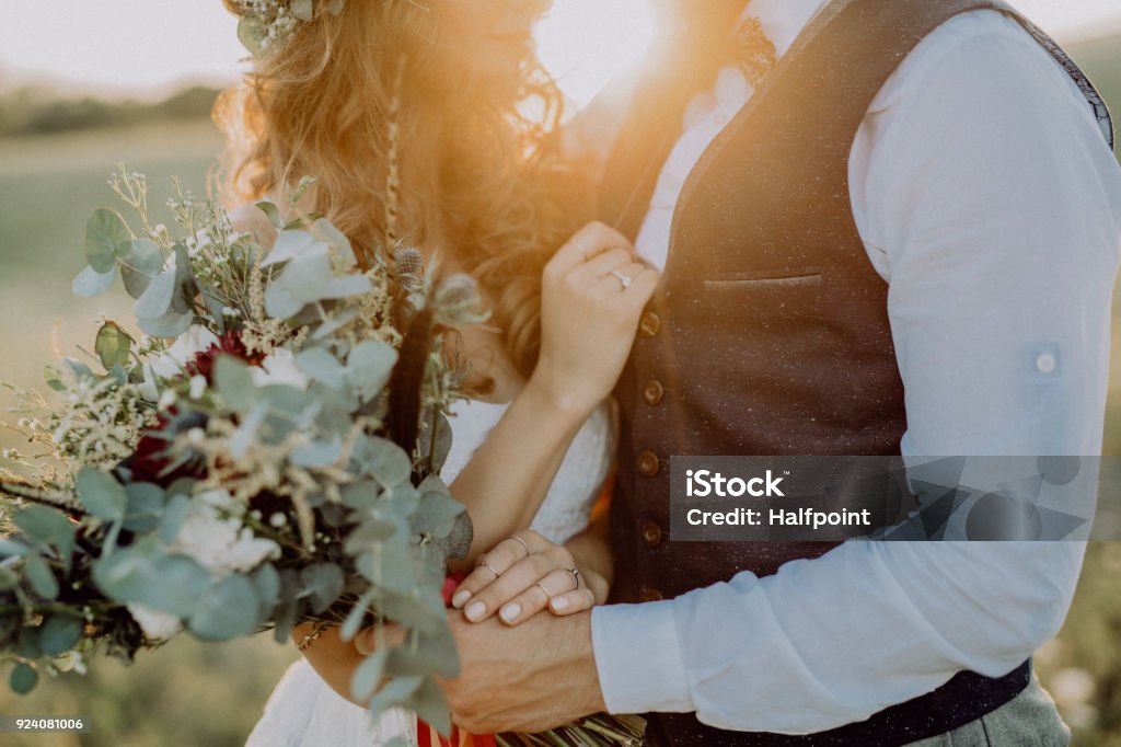 Beautiful bride and groom at sunset in green nature. Unrecognizable young bride and groom outside in green nature at romantic sunset. Wedding Stock Photo
