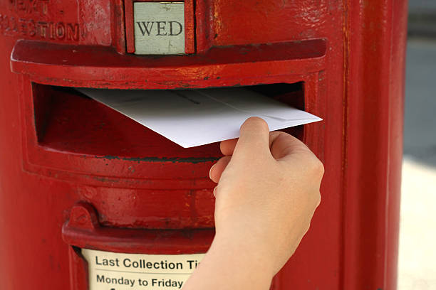 istock hand posting a  letter to red british postbox on street 92408300