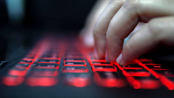 istock Unrecognized person typing on laptop computer red keyboard in dark, cinematic color graded footage 924083968