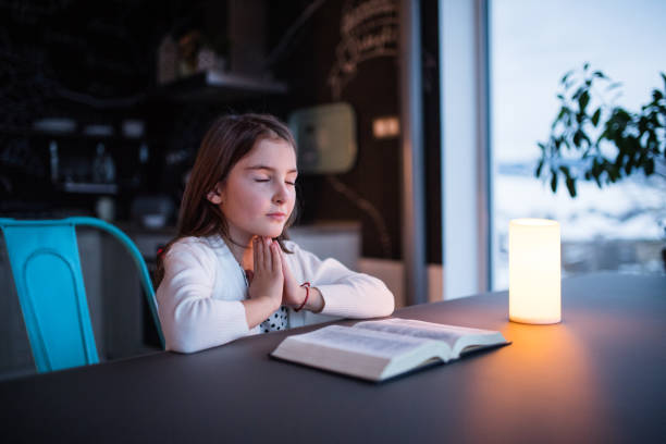 istock A small girl praying at home. 924083998