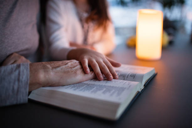 una bambina e una nonna che leggono la bibbia a casa. - family bible foto e immagini stock