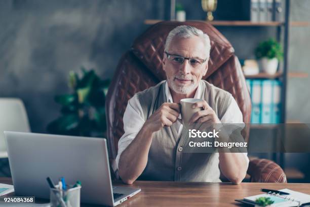 Cheerful Careless Excited Joyful Old Businessman With Bristle Is Pondering About Holidays Sitting On The Armchair In Front Of Laptop Stock Photo - Download Image Now