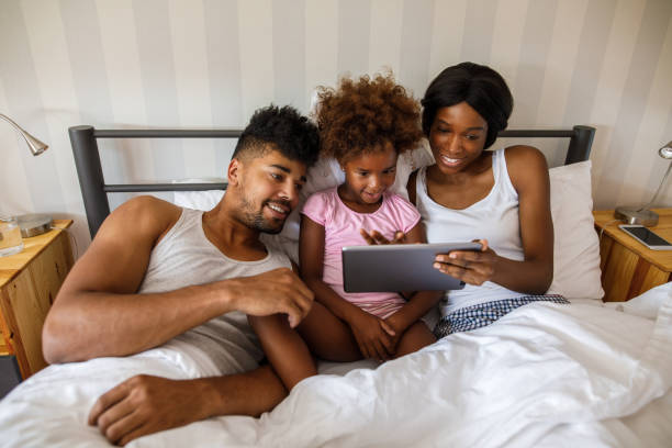 istock Happy couple using tablet with their daughter in bed 924091110