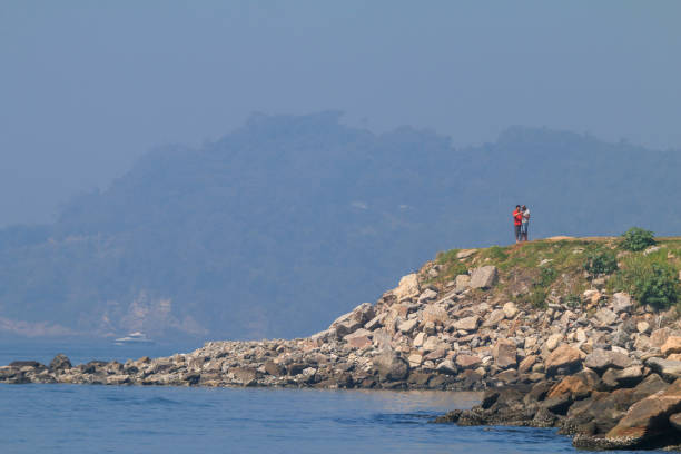 Two people walking at the edge of Guanabara Bay in Rio de Janeiro