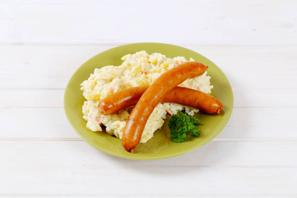 thin sausages with potato salad on green plate