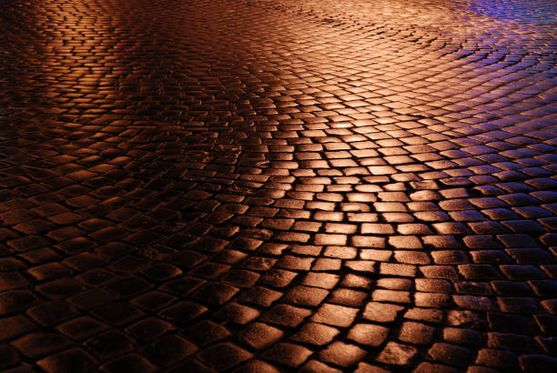 Night wet block cobblestone pavement with reflections of electric light, closeup