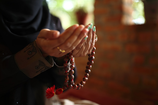 Close-up shot of a Muslim woman's hands holding rosary.