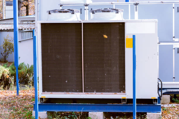 istock Gray commercial cooling unit for central ventilation system with big ventilation unit standing outdoor on the ground covered by fallen leaves 924116646