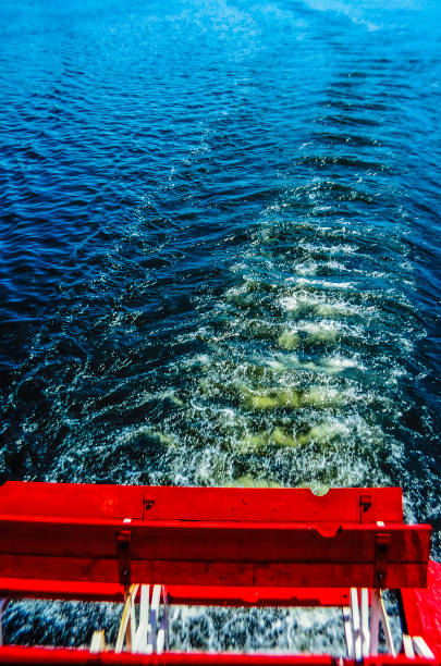 Close-up of a ship's red paddle-wheel and wave pattern in a river