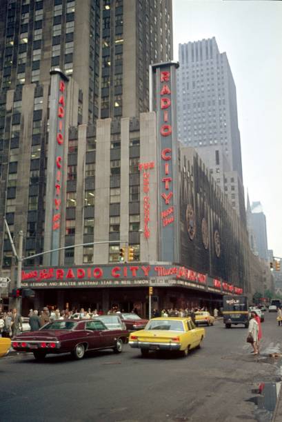 New York City, NYS, USA, 1968. Street scene on the W 50th.St. In the background the Building with the famous Radio City Music Hall. Furthermore: traffic, pedestrians, neon signs, advertising, and cars.