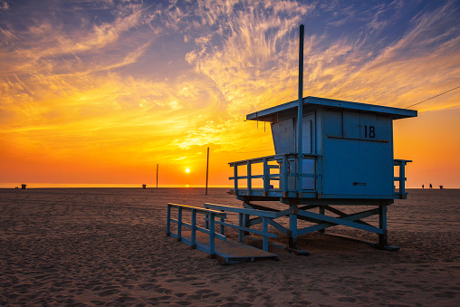 Sunset over Santa Monica beach with lifeguard observation tower in the foreground in Los Angeles, California