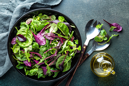 Fresh salad mix of baby spinach, arugula leaves, basil, chard and lambs lettuce. Salad bowl, healthy food, top view