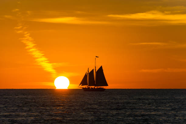 USA, Florida, Sailing ship next to orange sun as sunset near key west stock photo