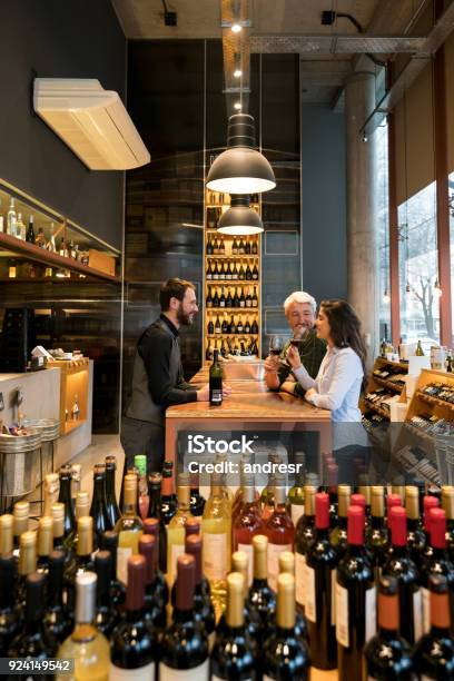 Friendly Sommelier Teaching A Couple About Wine Tasting At Winery Stock Photo - Download Image Now