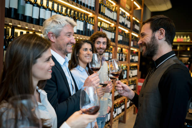 Group of people at a winery learning about wine with a friendly sommelier Group of people at a winery learning about wine with a friendly sommelier all looking very happy and smiling bar drink establishment stock pictures, royalty-free photos & images