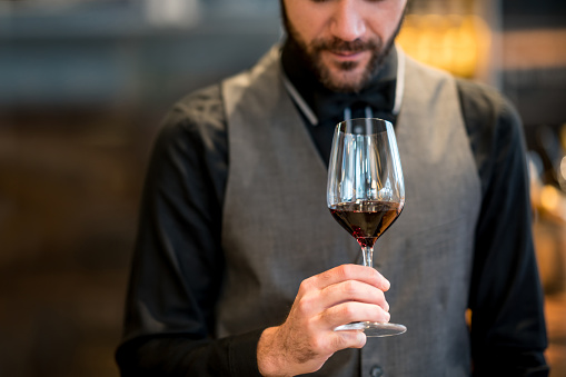 Unrecognizable male sommelier at a winery tasting and smelling a wine served in a wineglass