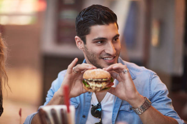 istock Young man holding burger in restaurant 924150192