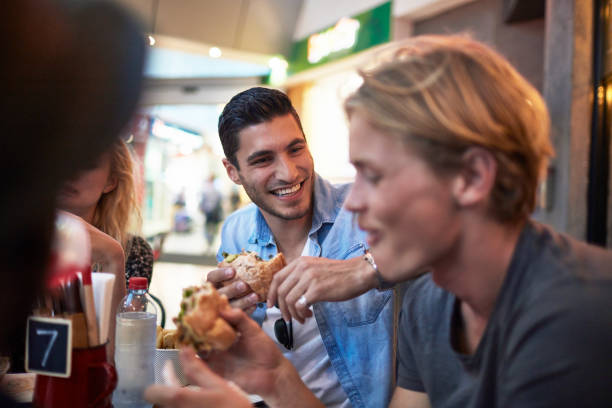 istock Man looking at friend having burger in restaurant 924150368
