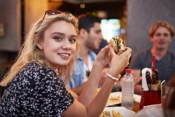istock Smiling young woman having burger in restaurant 924150544