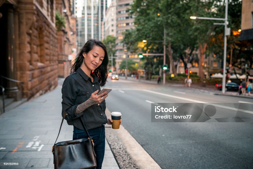 Young businesswoman waiting for taxi in Sydney Young businesswoman waiting for taxi in Sydney. She has a coffee to go. Women Stock Photo