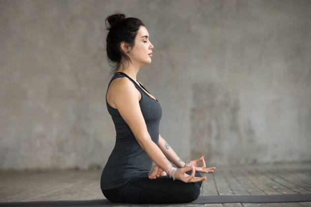 istock Young woman doing Sukhasana exercise, side view 924163606