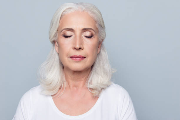 fechar o retrato da mulher madura concentrado confiante com rugas no rosto, com os olhos fechados, com nude compõem, isolado no fundo cinza - eyelid - fotografias e filmes do acervo