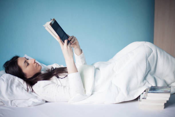 istock Woman reading a book in bed 924182152